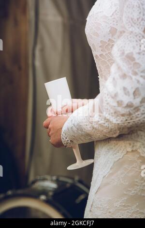 Eine Braut in einem Hochzeitskleid mit einer Sektflöte oder einem Weinglas Stockfoto