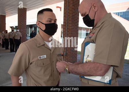 Captain Stephen Douglas Stephens, Kommandant der Naval Health Clinic Cherry Point, würdigt Dennis Velasco aus Dedeo, Guam, dem Corpsman der dritten Klasse des Krankenhauses, während einer Zeremonie an Bord der Klinik am Freitag, dem 12. März 2021, mit der Medaille für das Erreichen des Marine- und Marine-Korps. Stockfoto