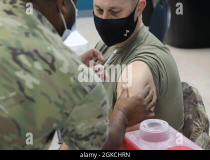 Armee Reserve Brig. General Justin Swanson, der als stellvertretender Generalkommandant des 1. Theater Sustainment Command nach Camp Arifjan, Kuwait, entsandt wurde, folgt der Spritze mit seinen Augen, kurz bevor er den Janssen Biotech COVID-19-Impfstoff bei der Einführung der Operation Med Spear am 13. März 2021 im Camp erhält. Swanson ist nur einer der General Officers und anderen leitenden Führungskräfte, die ihr Vertrauen in den Impfstoff unter Beweis gestellt haben. Stockfoto