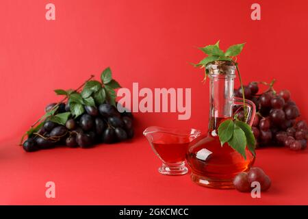 Konzept von Traubenessig auf rotem Hintergrund Stockfoto