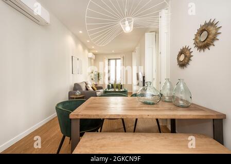 Unbehandelter Esstisch aus Holz mit Glaselementen oben in einer Ferienwohnung mit vielen Erkerfenstern zur Straße Stockfoto