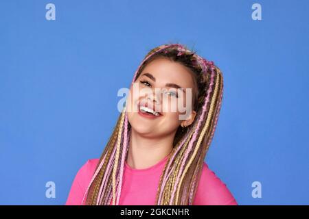 Frau mit Dreadlocks lächelt auf blauem Hintergrund Stockfoto