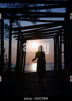 Eine Sonnenuntergangs-Silhouette stellt eine Frau am Strand dar Stockfoto