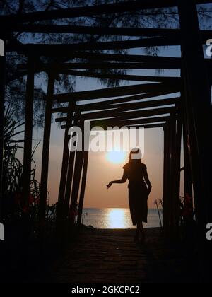 Eine Sonnenuntergangs-Silhouette stellt eine Frau am Strand dar Stockfoto