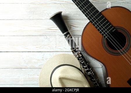 Klassische Gitarre, Klarinette und Hut auf weißem Holztisch Stockfoto