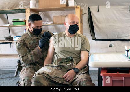 Sgt. Maj. John Shannon, Sergeant Major der Al Asad Air Base, erhält den Impfstoff COVID-19 von Sgt. Ryan Kamanu, Mediziner beim 466. Medical Company Area Support, am 15. März 2021 in der medizinischen Einrichtung Role II auf dem Luftwaffenstützpunkt Al Asad, Irak. Shannon und der Kommandant der Basis, Oberst Mark Coble, waren zwei von fast 400 Personen, die den Impfstoff während der ersten Impfwelle an der Basis erhielten. Stockfoto