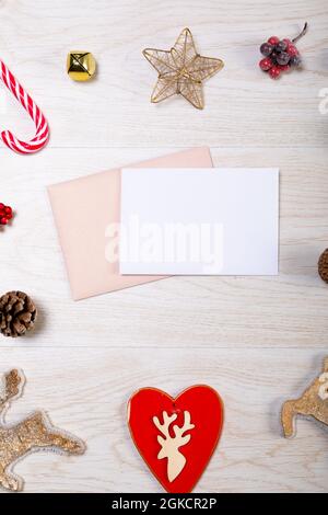 Komposition aus weißer Karte mit Kopierraum, Umschlag und weihnachtsschmuck auf Holzhintergrund Stockfoto