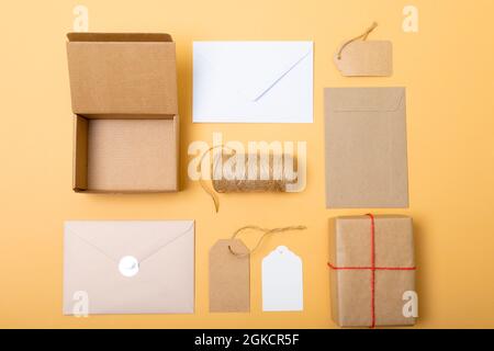 Zusammensetzung von Schachteln, Umschlägen und Geschenkanhänger auf gelbem Hintergrund Stockfoto
