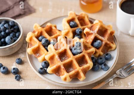 Belgische Waffeln mit Heidelbeeren auf dem Teller, Nahaufnahme. Süße runde Waffeln zum Frühstück oder Mittagessen Stockfoto