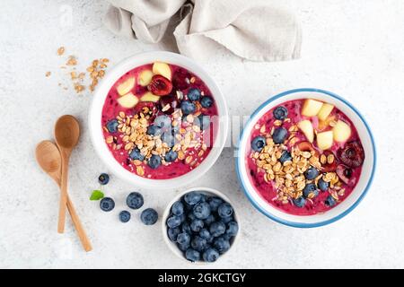 Lila Smoothie Schüssel Mit Belag Granola Beeren Früchte Auf Hellgrauem Zement Hintergrund, Ansicht Von Oben. Superfood Smoothie Bowl Stockfoto