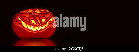 Leuchtender künstlerischer Halloween Kürbis auf schwarzem Panorama Hintergrund. Halloween-Webbanner Stockfoto
