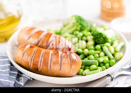 Gegrillte Putenwürste Serviert Mit Schneeerbsen Und Brokkoli Auf Dem Teller, Nahaufnahme, Selektiver Fokus Stockfoto