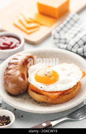 Frühstück Toast mit Cheddar-Käse, Spiegelei und Wurst auf einem Teller serviert, Nahaufnahme Blick. Englisches Frühstück Stockfoto