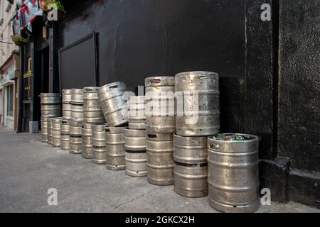 Bierfässer an einer schwarzen Wand am Auslass eines Pubs Stockfoto