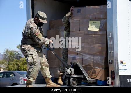 Arizona Army National Guard Pfc. Manuel Pina-Torres, 1-158. Infanterie-Bataillon, Infanterist, entlädt Kisten mit Lebensmitteln aus einem Lastwagen in einer Lebensmittelbank in Parker, Arizona., 16. März 2021. Die Kisten mit Lebensmitteln wurden von einer Lebensmittelbank in Gilbert, Arizona, transportiert, um sie als Teil der Unterstützung der Gemeindebedürfnisse während dieses Ausnahmezustands an lokale Bürger und Angehörige der Indianerstämme des Colorado River zu verteilen. Stockfoto