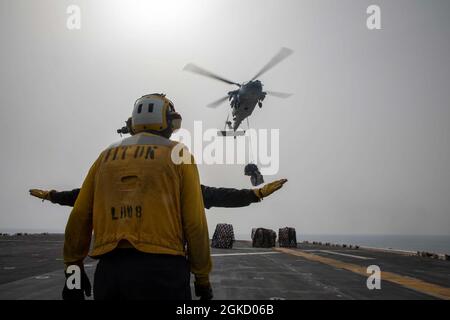 210314-N-AO823-1065 ARABIAN GULF (16. März 2021) – Mate Airmen der US-Marine Aviation Boatswain Jonathan Walker, in der Nähe von Und Ernest Pelicano signierte an Bord des amphibischen Angriffsschiffes USS Makin Island (LHD 8) einen MH-60S Sea Hawk, der dem Helicopter Sea Combat Squadron (HSC) 23 zugewiesen wurde, während einer Auffüllung auf See mit dem Trockenfracht- und Munitionsschiff USNS Carl Brashear (T-AKE 7). Die Makin Island Amphibious Ready Group und die 15. Marine Expeditionary Unit werden in das Einsatzgebiet der 5. US-Flotte eingesetzt, um Marineinoperationen zu unterstützen, um die maritime Stabilität und Sicherheit im Central R zu gewährleisten Stockfoto