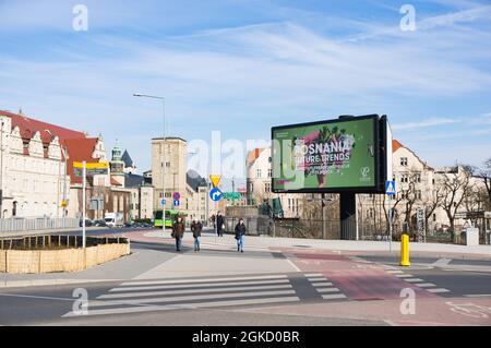 POZNAN, POLEN - 20. März 2018: Die Menschen, die auf einem Zebrastreifen neben einer großen Plakatwand von Posnania gehen Stockfoto