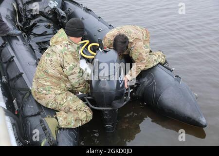 Zwei Soldaten der 3rd Special Forces Group (Airborne) installieren am 16. März 2021 an einem maritimen Einsatzpunkt auf dem Cape Fear River in der Nähe von Wilmington, North Carolina, an einem Kampfflugzeugfahrzeug, das auch als Zodiac bekannt ist, einen Motor aus dem Flugzeug. Die Zodiacs wurden von Mitgliedern der 3. SFG (A) verwendet, um im Rahmen einer maritimen Operation eine Langstreckenbewegung den Fluss hinauf durchzuführen. Stockfoto