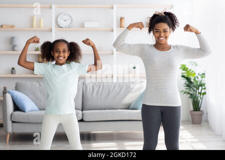 Starke afroamerikanische Mutter und Tochter zeigen ihre Muskeln Stockfoto