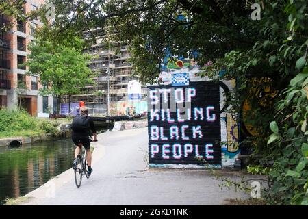 Radler auf dem Regent-Kanal in London, der an Graffiti vorbei fährt, „Stop Killing Black People“, inspiriert von Protesten der schwarzen Menschenleben Stockfoto