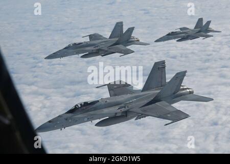 Eine Gruppe von Hornet-Flugzeugen der finnischen Luftwaffe F/A-18C fliegt in Formation, nachdem sie während der Übung Baltic Trident über Finnland am 17. März 2021 Treibstoff von einem Stratotanker-Flugzeug der KC-135 erhalten hat, das dem 100. Lufttankflügel zugewiesen wurde. Übung Baltic Trident ist eine gemeinsame Trainingsübung, um sicherzustellen, dass Luftwaffe und Luftbesatzung durch den Einsatz von Elementen agiler Kampfeinsätze tödliche Kampfkraft über das gesamte Spektrum militärischer Operationen hinweg liefern. Stockfoto