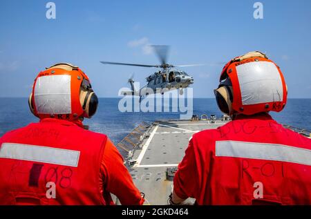 OSTCHINESISCHES MEER (17. März 2021) Matrosen, die dem Lenkraketen-Zerstörer USS Curtis Wilbur (DDG 54) der Arleigh Burke-Klasse zugewiesen wurden, beobachten während des Fluges ein MH-60R Seahawk Land. Curtis Wilbur wird der Task Force 71/Destroyer Squadron (DESRON) 15 zugewiesen, der größten Vorwärtsdresse der Marine und der wichtigsten Oberflächenkraft der US-Flotte der 7. Flotte Stockfoto