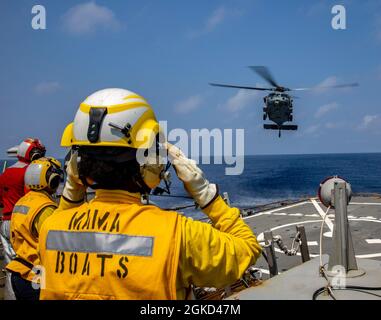 EAST CHINA SEA (17. März 2021) Boatswains Mate 2nd Class Subrina Hearne, die dem Arleigh Burke-Klasse Lenkraketen-Zerstörer USS Curtis Wilbur (DDG 54) zugewiesen wurde, signalisiert während des Fluges einem MH-60R Seahawk. Curtis Wilbur wird der Task Force 71/Destroyer Squadron (DESRON) 15 zugewiesen, der größten Vorwärtsdresse der Marine und der wichtigsten Oberflächenkraft der US-Flotte der 7. Flotte Stockfoto