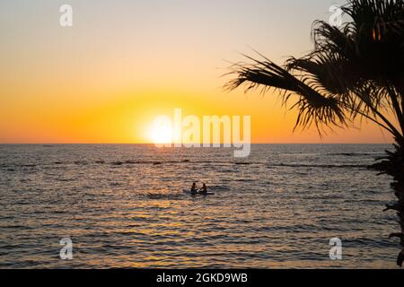 Zwei Frauen teilen sich das Paddelbrett bei Sonnenuntergang auf ruhigen Gewässern im mittelmeer in zypern. Zwei Mädchen paddeln auf SUP. Silhütte in der Ferne. Wasser Stockfoto