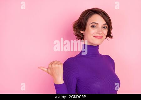 Foto von niedlichen Brünette tausendjährige Dame Punkt leeren Raum tragen violetten Pullover auf rosa Hintergrund isoliert Stockfoto