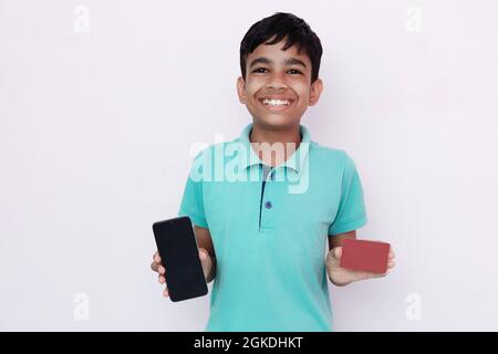 Online-Shopping. Aufgeregt Kerl zeigt Kamera Smartphone mit schwarzem leeren Bildschirm für Mock-up und rote Kreditkarte. Stockfoto