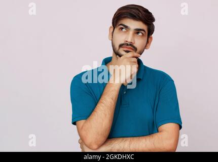 Junger Mann mit blauem Hemd, denkender Ausdruck auf isoliertem Hintergrund. Stockfoto