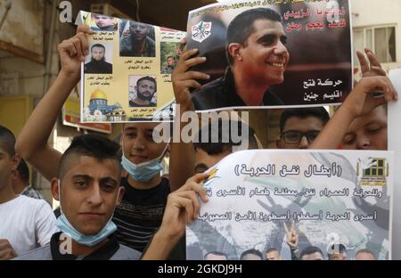 Jenin, Palästina. September 2021. Palästinenser sahen Porträts von Gefangenen, Zakaria al-Zubaidi und den vier Gefangenen, die während der Solidaritätsdemonstration mit palästinensischen Gefangenen, die in israelischen Gefängnissen festgehalten wurden, vor den Büros des Internationalen Komitees vom Roten Kreuz in der Stadt Jenbin aus dem Gefängnis von Jalameh entkommen waren. (Foto von Nasser Ishtayeh/SOPA Images/Sipa USA) Quelle: SIPA USA/Alamy Live News Stockfoto