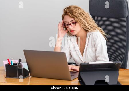 Die junge Frau arbeitet hart in ihrem Büro und beschäftigt sich mit Prblemen, mit moderner Ausrüstung. Hochwertige Fotos Stockfoto
