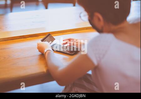 Rückansicht der Frau, die online auf dem Smartphone mit Kreditkarte einkauft. Stockfoto