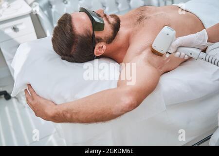 Mann in Schutzbrille während einer Lasertherapie-Sitzung Stockfoto