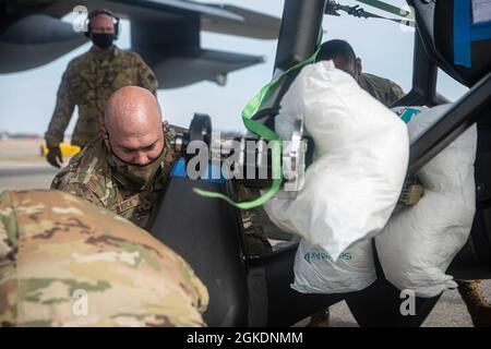 Ein Airman lädt Fracht auf einen HC-130J Combat King II am Springfield-Beckley Municipal Airport, Ohio, 23. März 2021. Die Ladung war ein ELEKTRONISCHES vertikales Start- und Landeflugzeug, das das 79. Rettungsgeschwader von Ohio nach Texas transportierte. Diese Transportbemühungen dienten als Proof of Concept, da der 355. Flügel plant, eVTOL in bevorstehende Übungen zu integrieren, um seine agilen Kampfarbeitsfähigkeiten zu fördern. Stockfoto