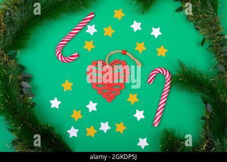 Komposition aus Süßigkeitenstöcken und weihnachtsdekorationen, eingerahmt von Tannenzweigen auf Grün Stockfoto