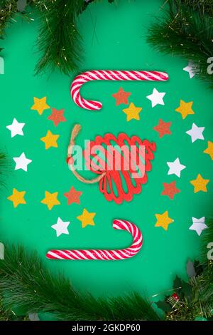 Komposition von Zuckerstöcken weihnachtsdekorationen eingerahmt von Tannenzweigen auf grünem Hintergrund Stockfoto