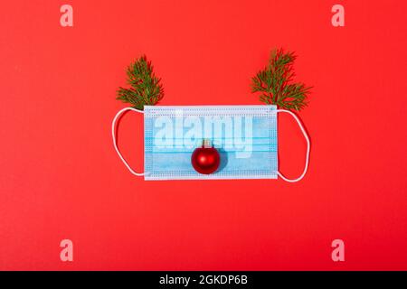 Zusammensetzung der Gesichtsmaske mit weihnachtsschmuck in Form von Rentieren auf grünem Hintergrund Stockfoto