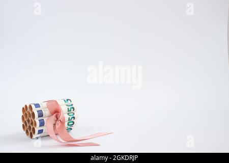 Banknoten von 50 Euro in Rollen, gebunden mit rosa Geschenkband auf weißem Hintergrund. Stockfoto