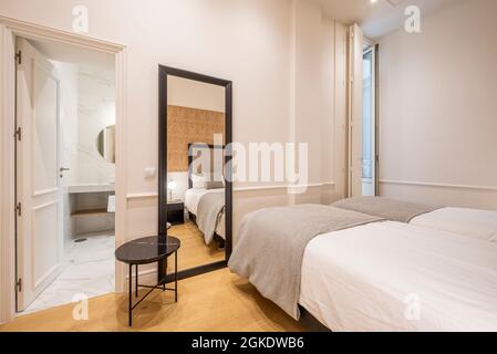 Schlafzimmer mit zwei Betten und Bad en Suite, großer Spiegel in der Ferienwohnung Stockfoto