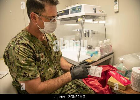 CAMP LEMONNIER, Dschibuti (25. März 2021) – U.S. Navy LT. Cmdr. Stephen M. Eggan aus Pittsburgh, Director for Science bei Naval Medical Research, erklärt, wie das Labor am 25. März 2021 in Camp Lemonnier, Dschibuti (CLDJ), virale RNA für COVID-19-Tests isolieren kann. CLDJ ist eine forward operativ operierende Basis, die es US-amerikanischen, alliierten und Partnernationstruppen ermöglicht, dort zu sein, wo und wann sie benötigt werden, um die Sicherheit in Europa, Afrika und Südwestasien zu gewährleisten. Stockfoto