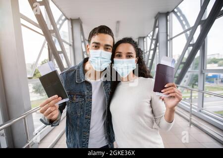 Arabische Ehegatten In Medizinischen Masken Posieren Mit Pässe Und Tickets Im Flughafen Stockfoto