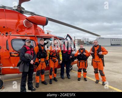 Eine Besatzung der Coast Guard Air Station Detroit posiert mit zwei geretteten Bootsfahrern in Port Clinton, Ohio, 26. März 2021. Die Besatzung hisste die Bootsfahrer von einem Schiff, das Wasser annahm. Foto der US-Küstenwache. Stockfoto