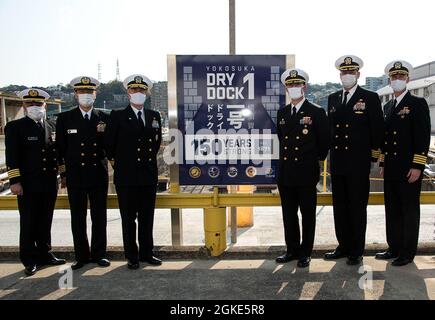 YOKOSUKA, Japan (26. März 2021) – Führung durch die US-Marine und die japanische Maritime Selbstverteidigungseinheit Yokosuka District, einschließlich rückseitiger ADM. Brian Fort, Commander, U.S. Naval Forces Japan/Navy Region Japan, Mitte links, und Capt. Rich Jarrett, Commander, Fleet Activities Yokosuka (CFAY), Mitte rechts, enthüllen ein Plakat zum 150. Jahrestag der Fertigstellung von Dry Dock 1. Die Anklagebank wurde offiziell während einer Zeremonie am 8. Februar 1871 (heute 28. März 1871) eröffnet. Früher von der kaiserlichen japanischen Marine verwendet, wird es seit 1974 gemeinsam von der US-Marine und Japan verwendet. Für Mo Stockfoto