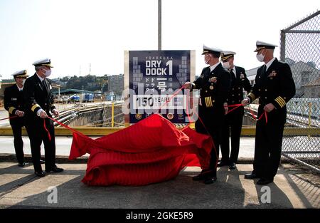 YOKOSUKA, Japan (26. März 2021) – Führung durch die US-Marine und die japanische Maritime Selbstverteidigungseinheit Yokosuka District, einschließlich rückseitiger ADM. Brian Fort, Commander, U.S. Naval Forces Japan/Navy Region Japan, Mitte links, und Capt. Rich Jarrett, Commander, Fleet Activities Yokosuka (CFAY), Mitte rechts, enthüllen ein Plakat zum 150. Jahrestag der Fertigstellung von Dry Dock 1. Die Anklagebank wurde offiziell während einer Zeremonie am 8. Februar 1871 (heute 28. März 1871) eröffnet. Früher von der kaiserlichen japanischen Marine verwendet, wird es seit 1974 gemeinsam von der US-Marine und Japan verwendet. Für Mo Stockfoto