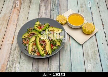 Gehackter Avocado-Salat, rote Zwiebel und Tomate, gehackte frische Petersilie und Schüssel mit gelbem Chili Stockfoto