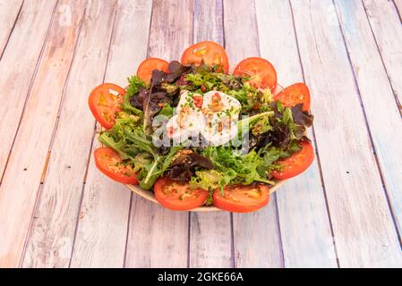 Ziegenkäse-Salat mit getrockneten Früchten, Tomaten in Scheiben geschnitten, Sprossen mit verschiedenen Salaten und Sesamsamen Stockfoto