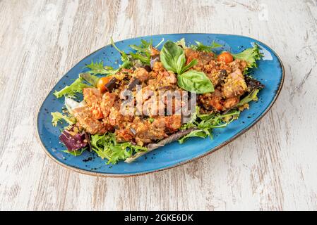 firenzalat mit viel Thunfischkonserven, Salat und Basilikum mit Kirschtomaten auf einem blauen Teller Stockfoto