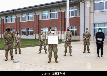 Soldaten, die der First Army Division East, der 4th Cavalry Multi-Functional Training Brigade, zugewiesen wurden, halten ein Zeichen, um für ein Gruppenfoto zu posieren, nachdem sie ihre zweite Dosis des COVID-19-Impfstoffs am Freitag, den 26. März 2021, erhalten haben. Stockfoto